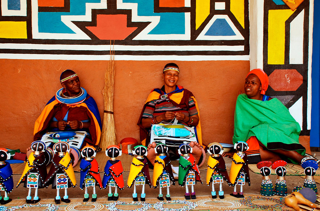Женщины племени ндебеле продают кукол ручной работы на ярмарке в этнографическом комплексе