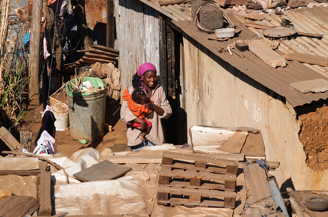 Женщина с ребенком в коммуне Соуэто. Соуэто — огромный город, застроенный лачугами, в которых живут бедняки. Во времена апартеида — место для принудительного проживания африканского населения
